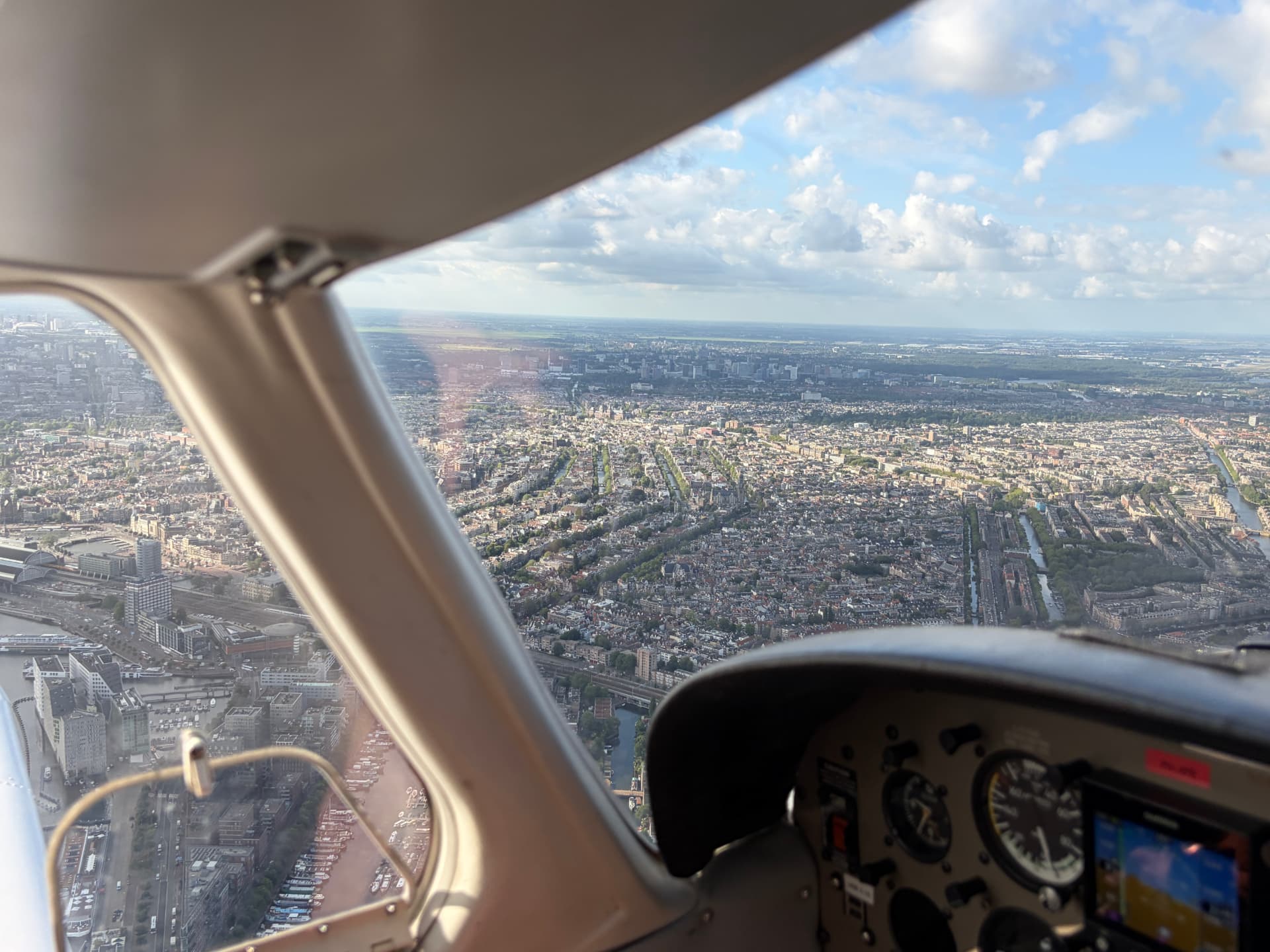 Uitzicht op de Amsterdamse grachtengordel vanuit de cockpit van een Piper PA-28 tijdens een rondvlucht