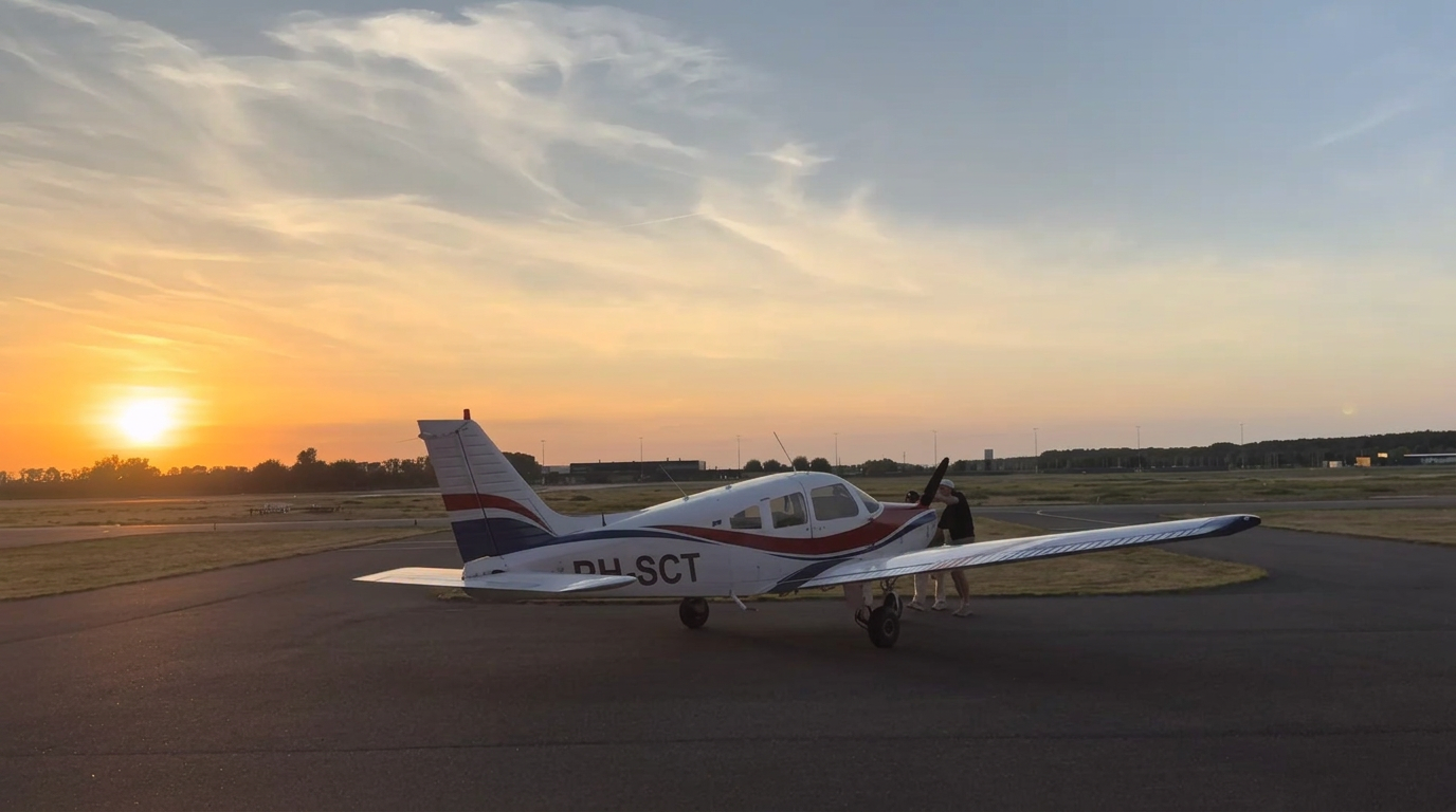 Piper PA-28 Warrior II bij zonsondergang op het platform van Lelystad Airport klaar voor een rondvlucht boven Nederland