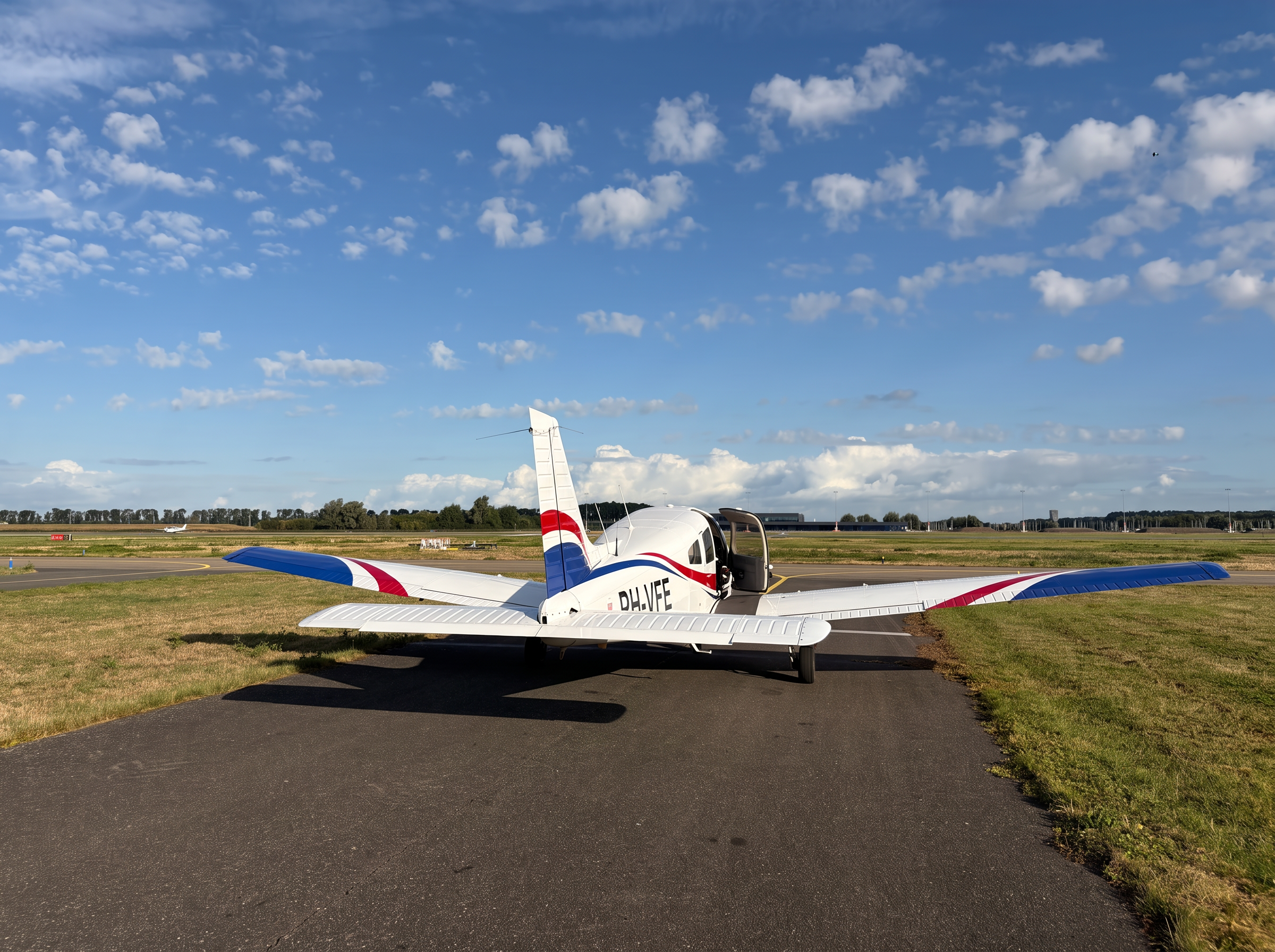 Piper PA-28 Warrior III met open cabinedeur op de taxibaan van Lelystad Airport voor een rondvlucht Amsterdam of Texel